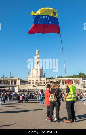 Fatima, Portugal - May 12, 2019: Group of pilgrims with flag of Venezuela fluttering in the Shrine of Fatima, Portugal. Stock Photo