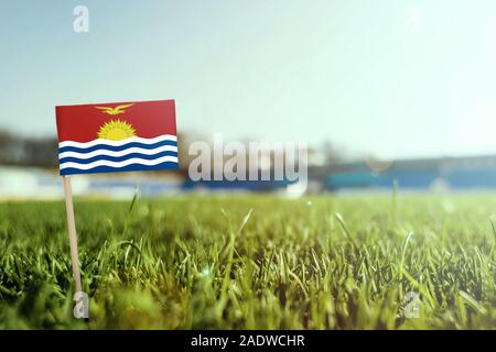 Miniature stick Kiribati flag on green grass, close up sunny field. Stadium background, copy space for text. Stock Photo