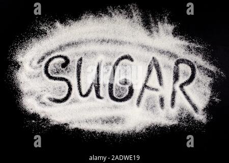 Word sugar, hand lettering on black background. The text is written on a pile of powdered white granulated sugar. Sugar eating harm concept Stock Photo