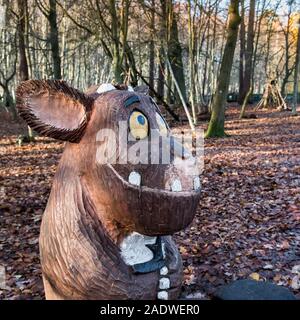 A wooden carved statue of a Baby Gruffalo in an autumnal Thorndon Park North in Brentwood in Essex. Stock Photo