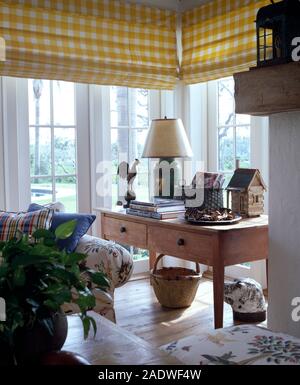 Yellow+white checked blind on French windows in a light and airy country living room Stock Photo