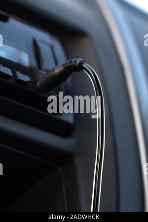 Aux cable inserting on car audio to play music from mobile phone. Stock Photo