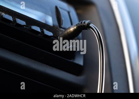 Aux cable inserting on car audio to play music from mobile phone. Stock Photo