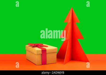 Gift box and envelope with red wodden Christmas tree on a natural brown background with scattered hearts. Stock Photo