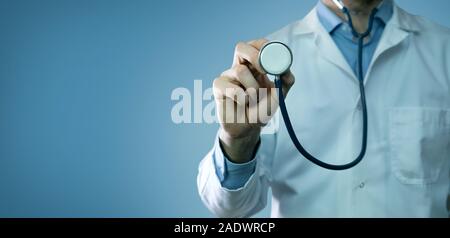 healthcare and medicine - doctor in white coat holding stethoscope on blue background. copy space Stock Photo
