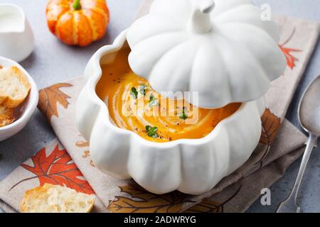 Pumpkin and carrot cream soup in creative bowl. Grey background. Close up Stock Photo