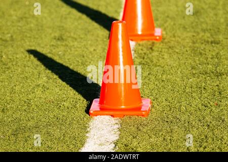 Orange cones on a white line on a green turf field Stock Photo