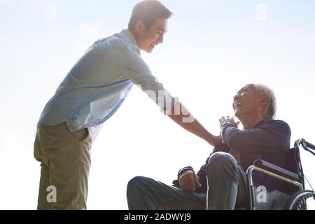 young asian adult son giving dad a pat on the shoulder, happy and smiling Stock Photo