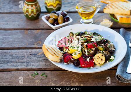 Grilled vegetables salad with feta cheese in white plate. Wooden background. Copy space Stock Photo
