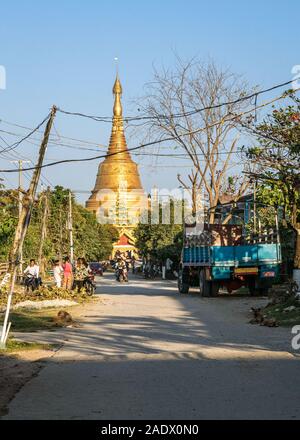 Local people going about their everyday life in a  small burmese town of Taungoo, Myanmar with the famous Swesandaw pagoda in the background. Stock Photo