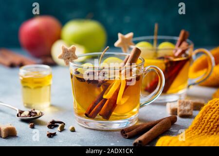 Apple mulled cider with spices in glass cup. Grey stone background. Close up Stock Photo