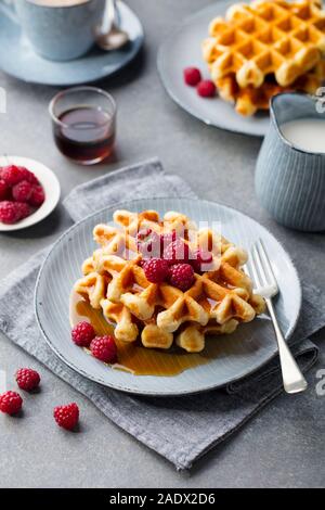 Belgian waffles with maple syrup and fresh raspberry. Grey background Stock Photo