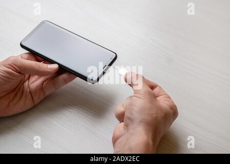 Eject SIM and mini SD card from phone with pin, ejector tool Stock Photo