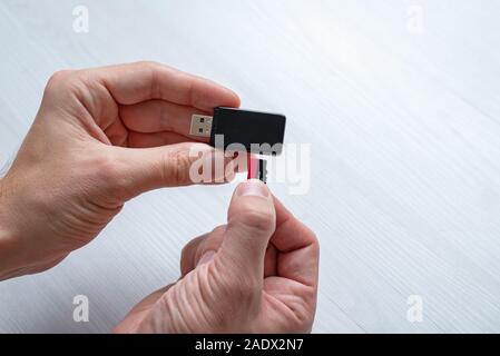 Inserting mini SD memory card in card reader concept. Hand holding memory card and inserts it into the usb reader. Stock Photo