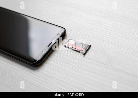 SIM card and memory card in adapter beside smart phone on desk close-up Stock Photo