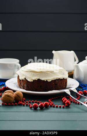 Traditional fruit cake minimalist style. Tasty chocolate cake with cream cheese and white teaware on dark blue background copyspace Stock Photo