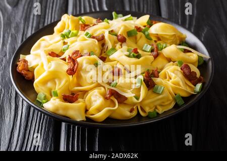 Serving tortelloni pasta with bacon and cheese close-up in a plate on the table. horizontal Stock Photo
