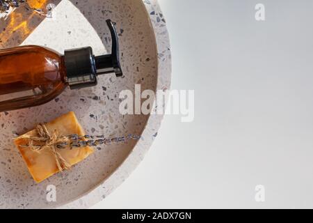 Glass bottle and natural soap on stone tray, top view. Stock Photo