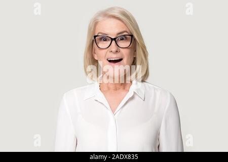 Old woman in glasses sincerely surprised looking at camera Stock Photo