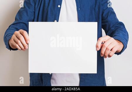 Man in blue shirt holding white blank paper Stock Photo