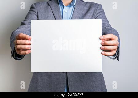 Unrecognisable man in grey suit holding a blank white board Stock Photo