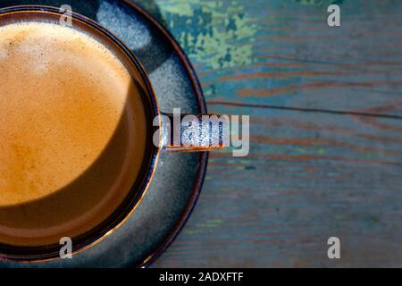 Flat lay cappuccino or latte with frothy foam, blue coffee cup top view closeup on wooden background in sun light. Cafe and bar, barista lifestyle art Stock Photo
