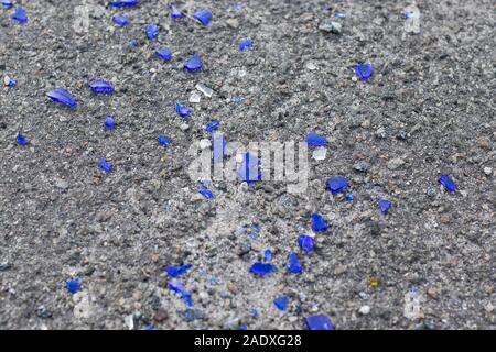 Small pieces of broken blue glass on the asphalt. Broken blue bottle texture Stock Photo