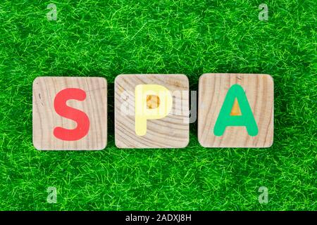 Word SPA written in wood letters laid on grass. Concept of wellness background Stock Photo