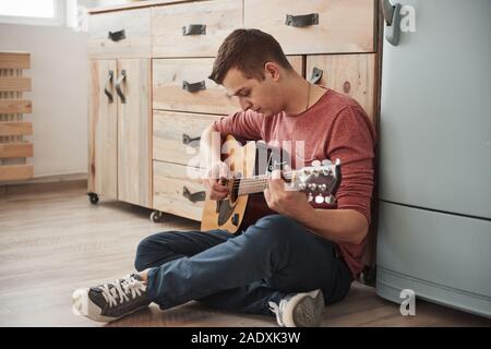 Musician plays on acoustic guitar at home in the kitchen at his weekend Stock Photo