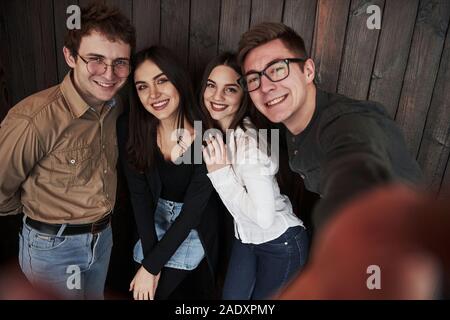 What to do when you waiting. Taking selfie. Close up front view of friends. Man in sunglasses in the room Stock Photo