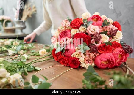 European floral shop concept. Florist woman creates red beautiful bouquet of mixed flowers. Handsome fresh bunch. Education, master class and Stock Photo