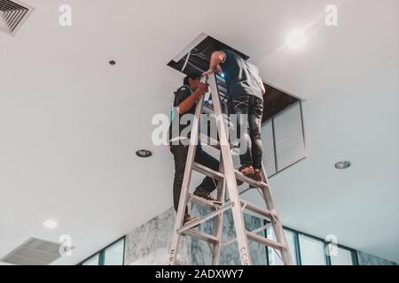 Worker fixing malfunctioned HVAC air condition system in office building Stock Photo