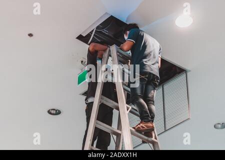 Worker fixing malfunctioned HVAC air condition system in office building Stock Photo