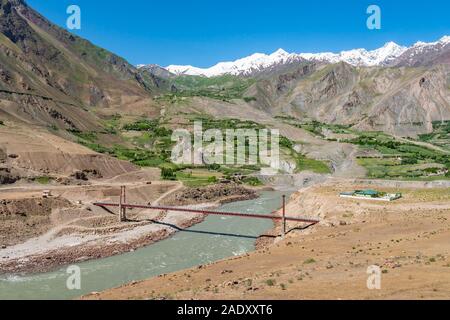 Qalai Khumb to Khorog Pamir Highway Picturesque Panj River Valley View of a Bridge near Rushon on a Sunny Blue Sky Day Stock Photo