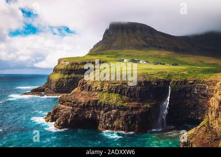 Gasadalur village and its iconic waterfall under strong wind, Vagar, Faroe Islands, Denmark