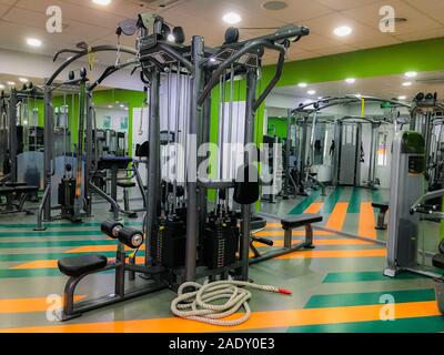 Gym or fitness hall interior with equipment. Machines, barbells, rods, disks, weight, dumbbells. Sport, bodybuilding, lifestyle and people concept Stock Photo
