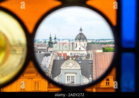Detail of the Krakow city panorama from the Town Hall Tower through window with colored stained glass windows. Upper part of old gorgeous home and St. Stock Photo