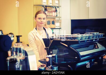 Portrait of smiling mid owner standing behind counter while looking at camera – Beautiful woman at cafeteria welcoming customers - Barista working Stock Photo