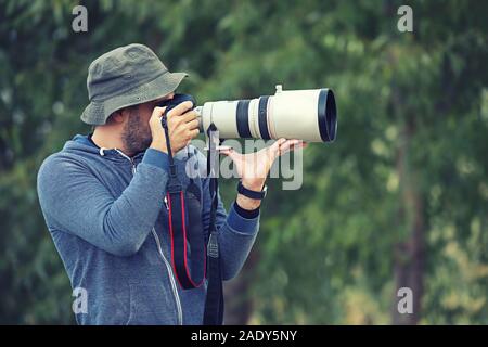 Professional nature and wildlife photographer outdoor hand holding camera with big pro lens taking pictures Stock Photo