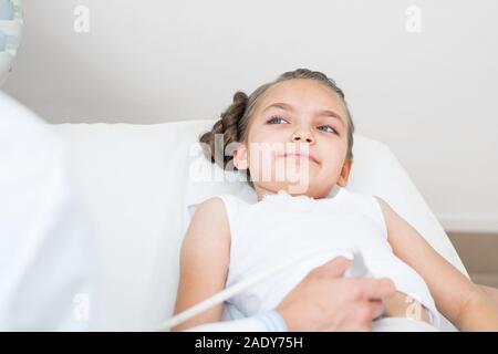 Sonographer moving transducer on belly of girl Stock Photo