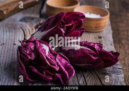 Fresh baby radicchio on wooden board. Healthy vegan plant based food on rustic wooden table Stock Photo