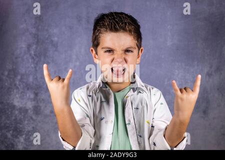 Happy cute child screaming and doing heavy metal rock sign Stock Photo