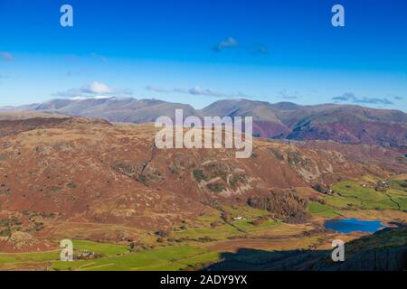 Looking down Wetherlam Edge to Little Langdale tarn and Helvellyn in the distance, Cumbria England. Stock Photo