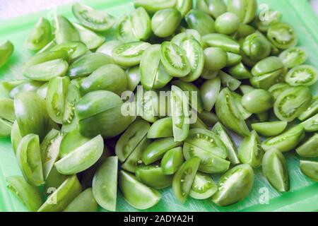 Chopped Green tomatoes on a green chopping board. Stock Photo