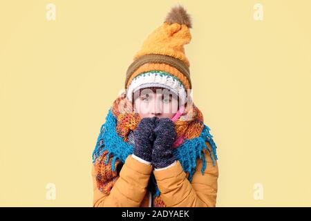 Frozen Girl in hat and scar shivering because of winter weather. Studio shot Stock Photo