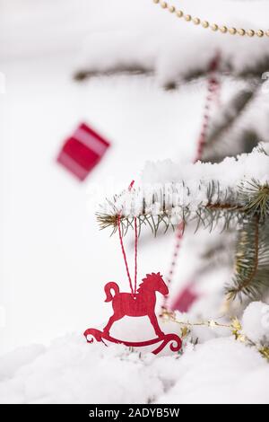 Christmas decorations on a beautiful tree with snow, outdoors. Season holidays and celebrations. Traditional Christmas tree decor. Stock Photo