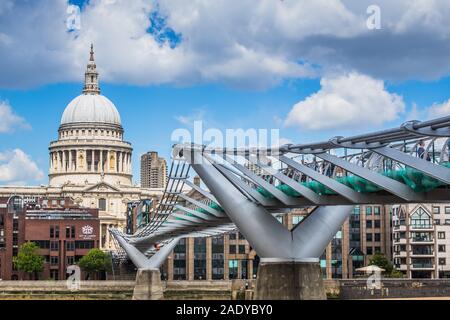 Paul's Cathedral and the Millennium Bridge, taken from the south side of the Thames River embankment on a sunny day with puffy clouds.