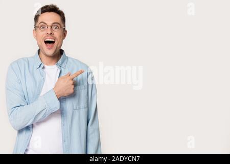 Surprised young man showing by forefinger at blank copy space Stock Photo