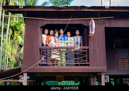 Six young girls watch from a window in their wooden boarding house in a small village along the Chindwin River in northwestern Myanmar (Burma) Stock Photo