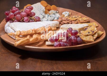 Wooden cheese platter with brie, assorted cheeses, red grapes, crackers and nuts Stock Photo